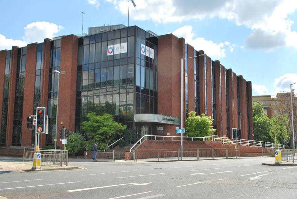Modern red brick and glass building for Bucks New University at a city street corner.